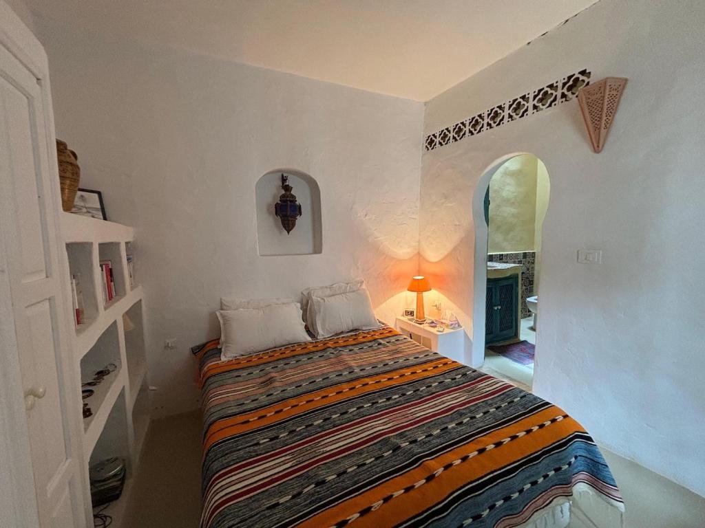 ein Schlafzimmer mit einem Bett in einem Zimmer mit einem Spiegel in der Unterkunft Dar Temna Renovated traditional house in Erriadh
