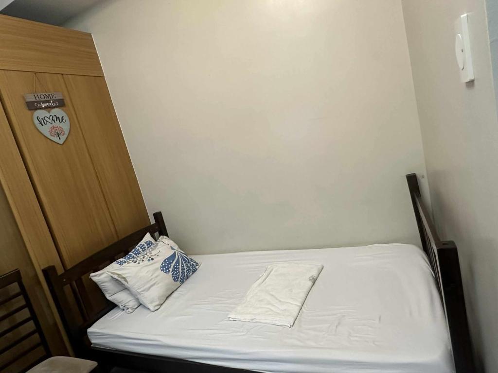 a small room with a bed with white sheets and pillows at Shell Residences Staycation in Sampong