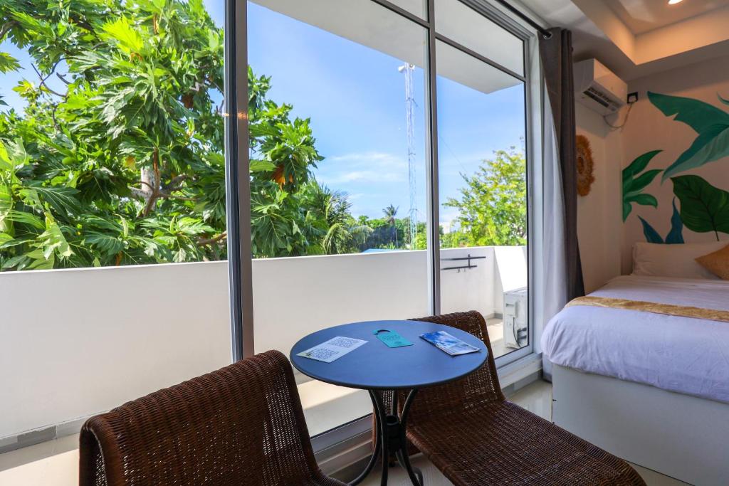 una habitación con una cama, una mesa y sillas en Sands Garden Hotel, en Thoddoo