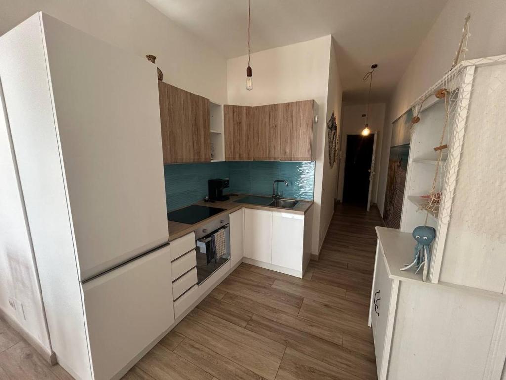 a kitchen with white cabinets and wooden floors at Attico Galilei Fronte Mare by Salentoville Gallipoli in Gallipoli