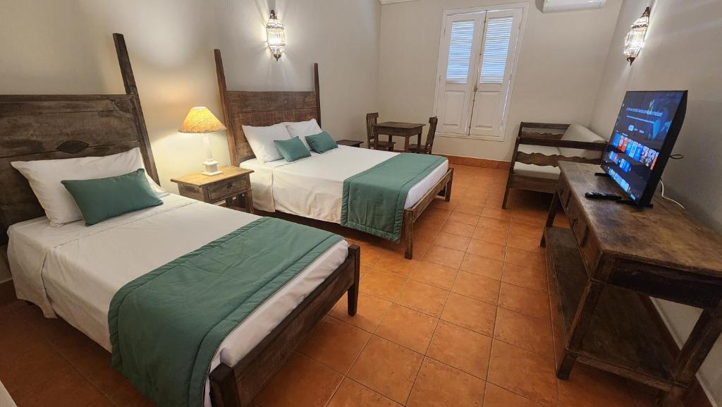 a hotel room with two beds and a television at Quinta das Águas Hotel in Itapira