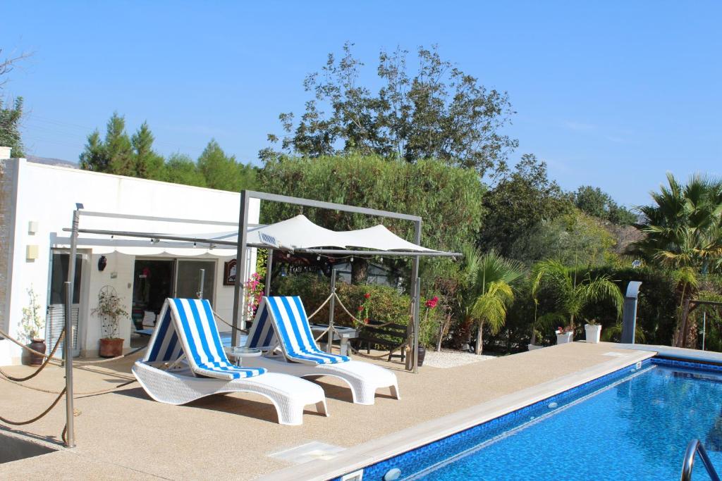 Dos sillas y una sombrilla junto a una piscina. en St.George's Country Retreat, en Limassol