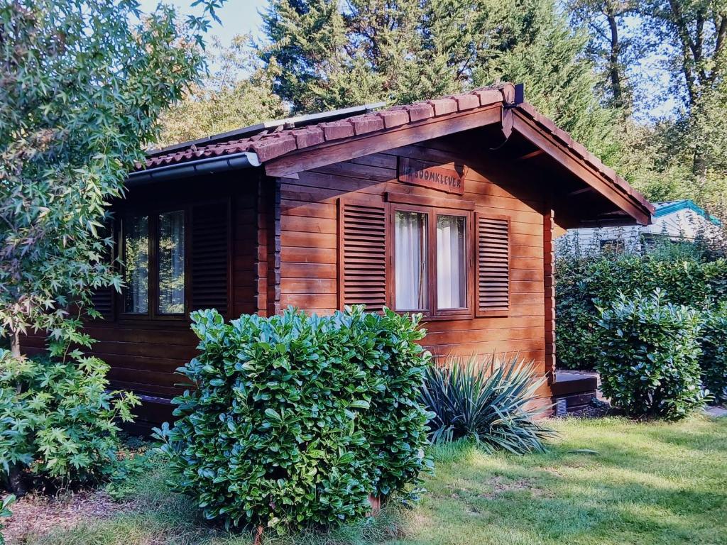 a small wooden cabin with a window and bushes at Lekker knus in de Huismus in Diffelen