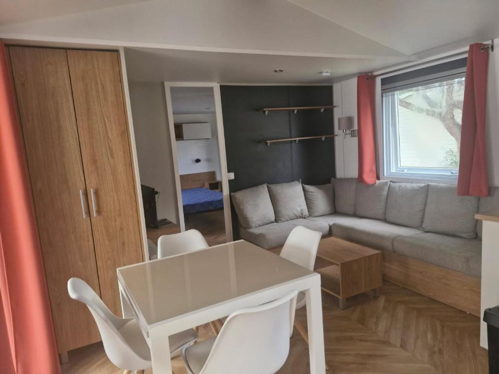 a living room with a table and a couch at Mobil home contis lettes 40170 in Saint-Magne