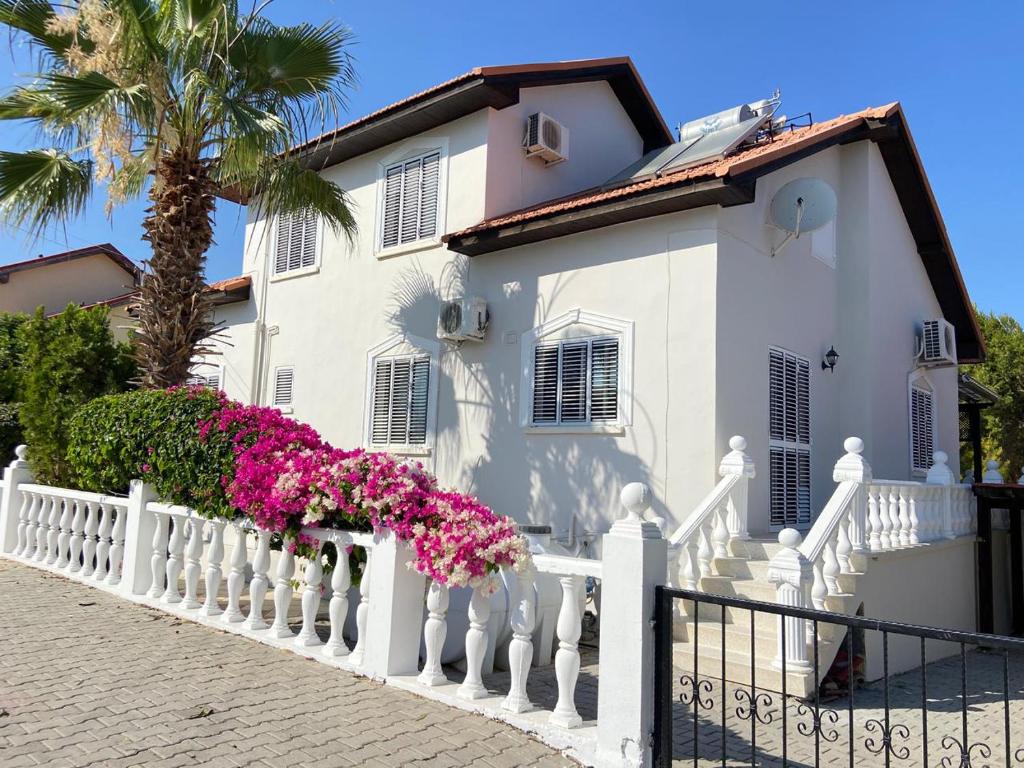 ein weißes Haus mit einem weißen Zaun und rosa Blumen in der Unterkunft Luxury 5-Bedroom Villa Sarcon 88 on seaside in Karaoğlanoğlu