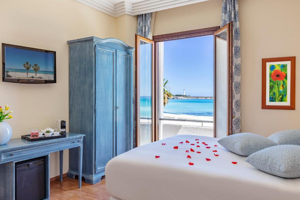 a bedroom with a bed with a view of the ocean at Mira Spiaggia in San Vito lo Capo