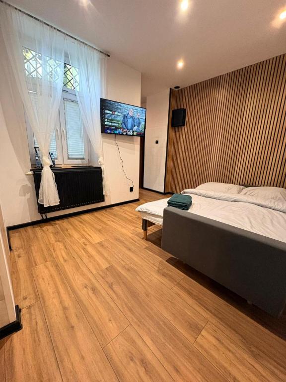 a bedroom with a bed and a flat screen tv at Zakątek Centrum 3 in Suwałki