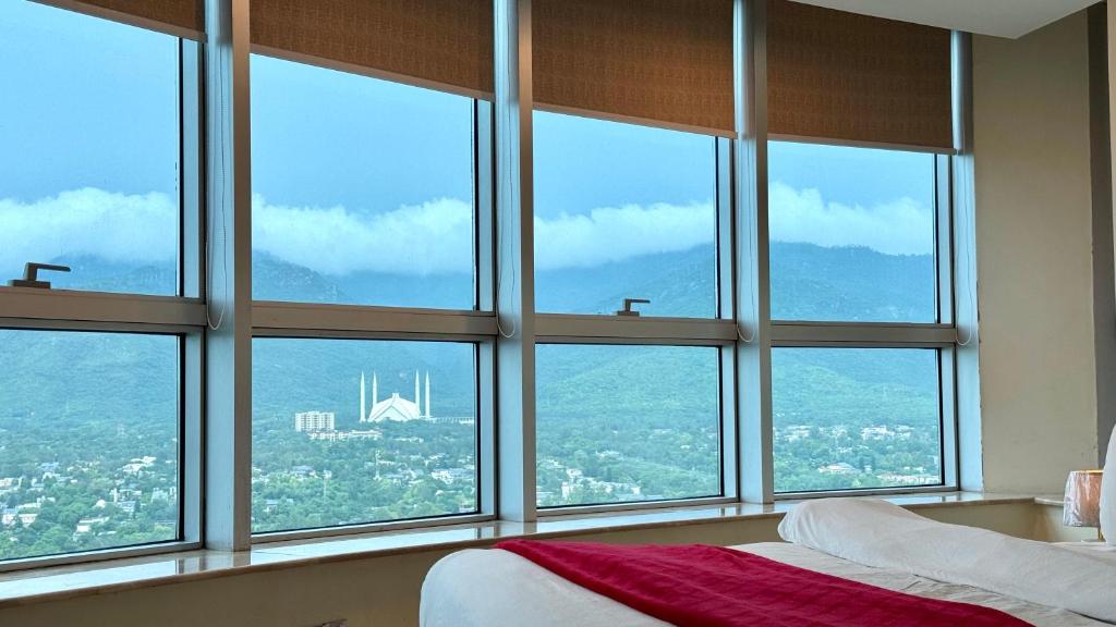 a bedroom with four windows with a view of a bridge at Centaurus Two Bed Mountain View in Islamabad