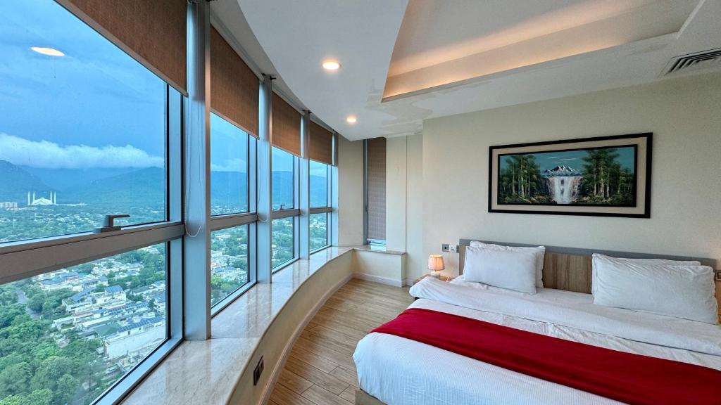 a bedroom with a large bed and large windows at Centaurus Three Bed Mountain View in Islamabad