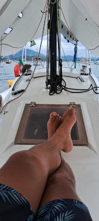 een man die op de zijkant van een boot ligt bij Veleiro Alpha 22 Privativo in Paraty