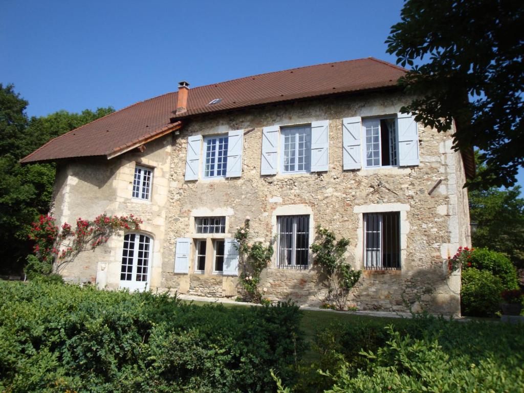 una antigua casa de piedra con techo rojo en Chambre Chez L'habitant, en Sermérieu