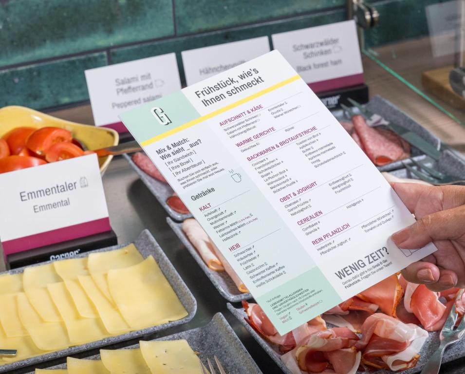una persona sosteniendo un menú frente a carnes y quesos en Garner Hotel Bremen North by IHG, en Bremen