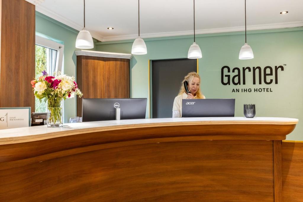 a woman standing at a reception desk in an office at Garner Hotel Bremen North by IHG in Bremen