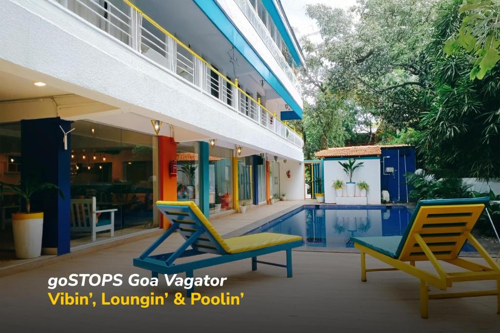 a villa with a swimming pool and two chairs at goSTOPS PLUS Goa, Vagator in Goa Velha