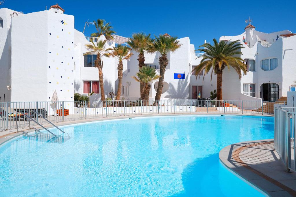 a large swimming pool with palm trees and buildings at Las Tortugas Bungalow Beach in Arona