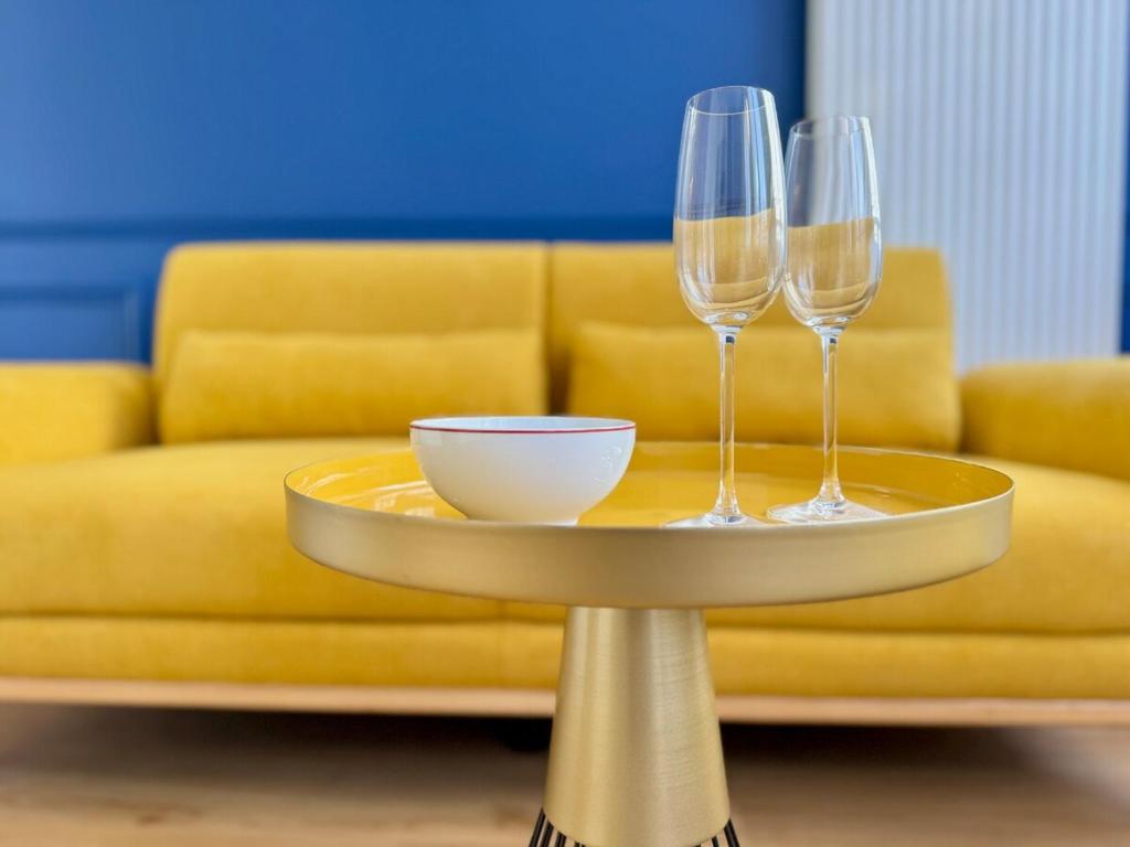 two wine glasses on a table in front of a couch at Wellness Suite Ponsardin 1 - Reims Centre in Reims