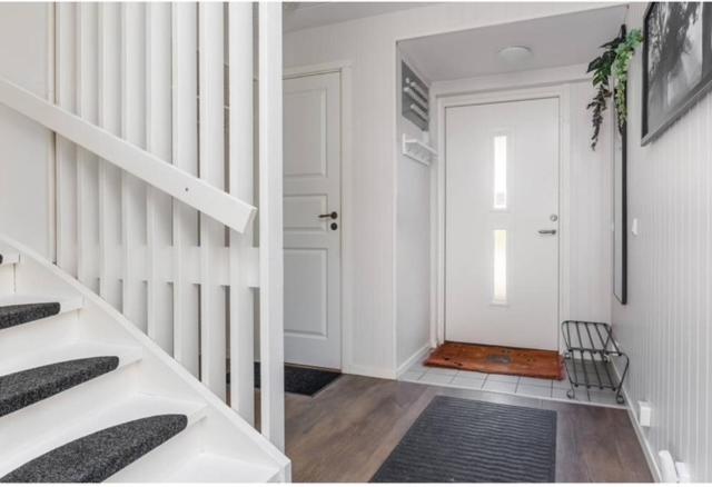 a hallway with a white staircase and a white door at Day To Day Motel in Ludvika