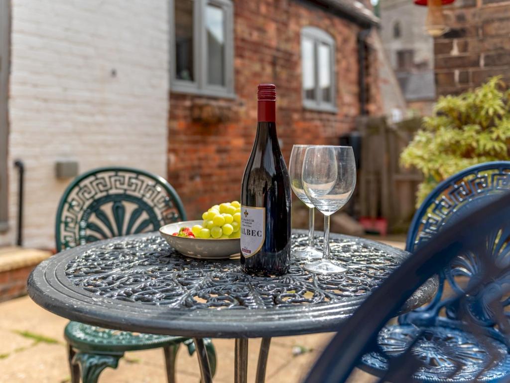 a bottle of wine and a bowl of grapes on a table at Pass the Keys Charming Granary Escape Garden Countryside in Much Wenlock