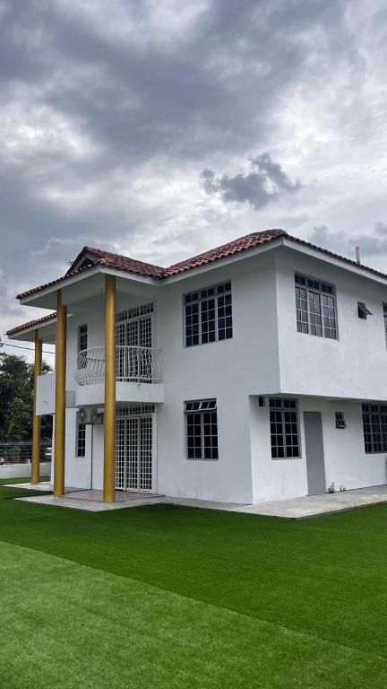 a white building with a green lawn in front of it at Anggun's palace in Pasir Gudang