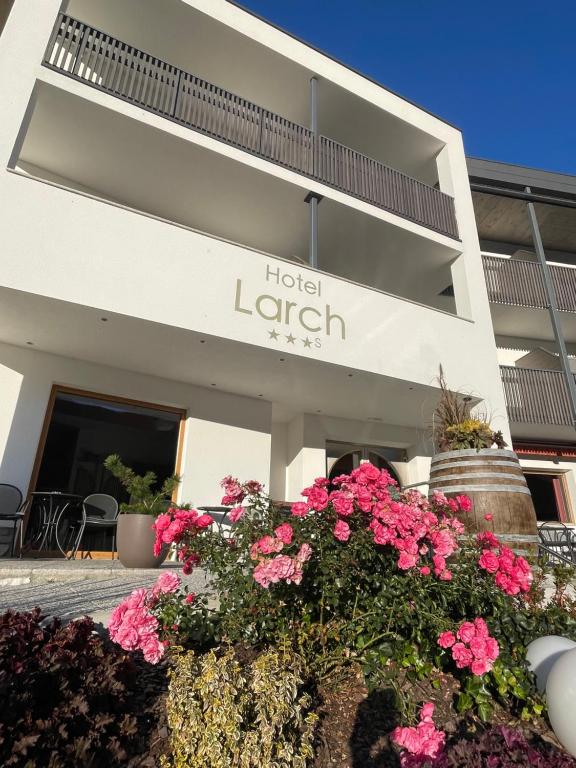 a hotel garden with flowers in front of a building at Hotel Larch in Campo di Trens