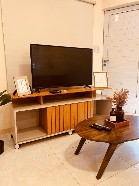 ClorindaにあるSHINY Houseの木製のスタンドとコーヒーテーブルの上に置かれた薄型テレビ