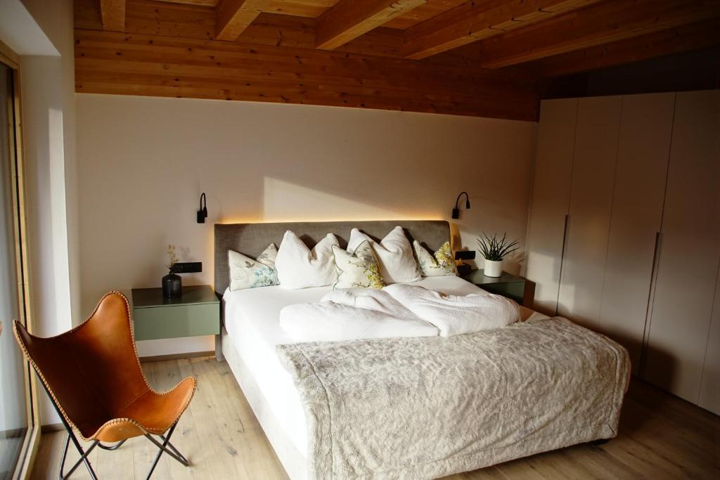 a bedroom with a large white bed and a chair at MALIA - Alpine Hideaway in Pertisau