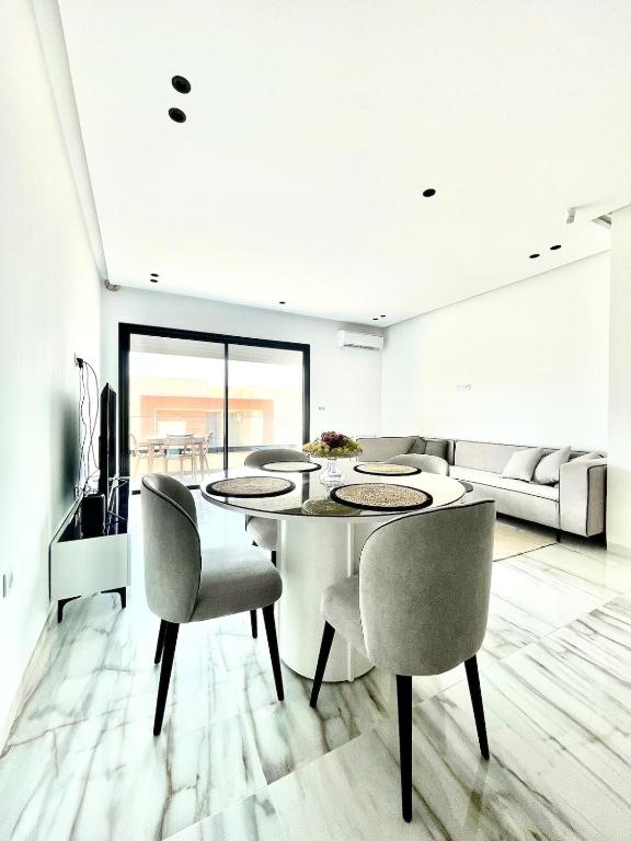 a white dining room with a table and chairs at Maison Miralin Beach in Hammam Sousse