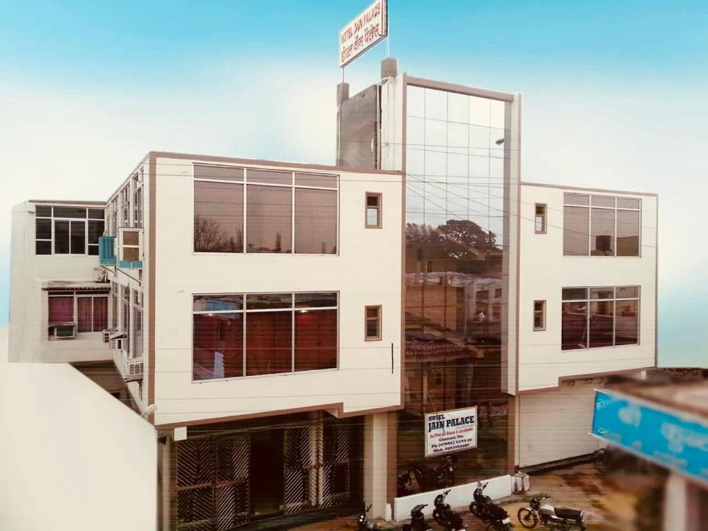 a tall white building with a sign on top of it at Hotel jain palace in Chhatarpur