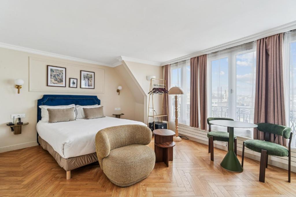Un dormitorio con una cama, una silla y una mesa. en Hotel Le Clery, en París