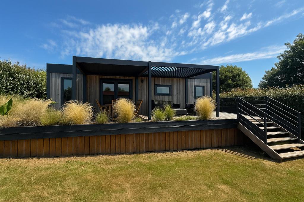 a modern house with a black exterior at Mobilhome moderne avec grande terrasse, pergola, HUDIMESNIL in Hudimesnil