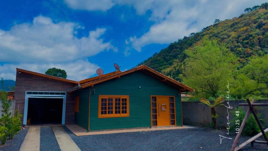 una casa verde con garaje y una montaña en Casa no centro de Urubici Dutra Borba, en Urubici