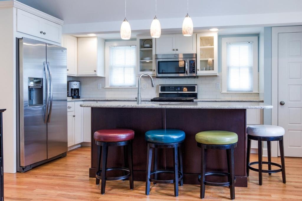 a kitchen with a counter with four bar stools at Beautiful & Romantic 1BR Cottage w/Beach Locker in Ocean Grove