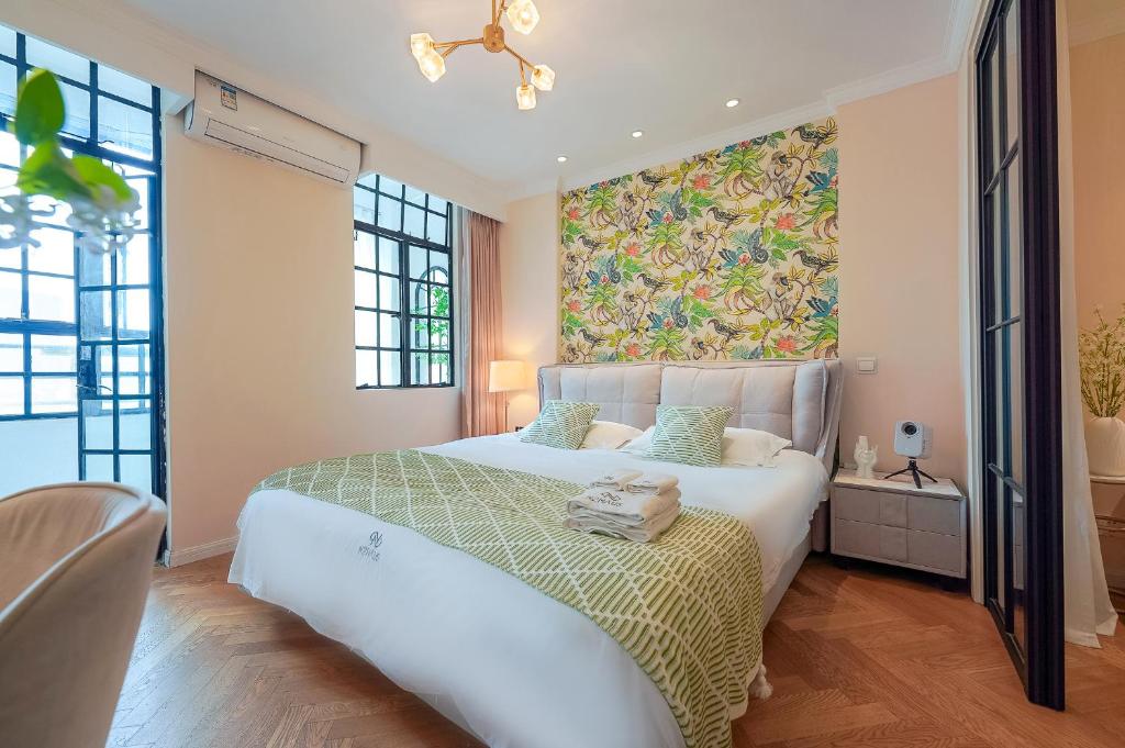 a bedroom with a large white bed with a painting on the wall at Shanghai Zighouse--The Bund Premium Apartment Suites in Shanghai