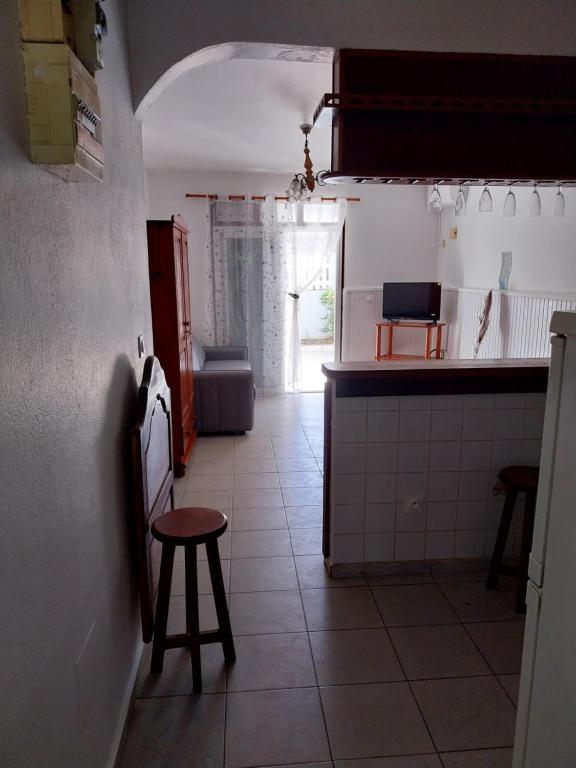 a kitchen with a counter and a table and a stool at Chez Rosalie in Lamentin