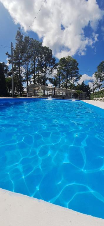 a large blue swimming pool with trees in the background at Apart hotel Amter in Fray Bentos