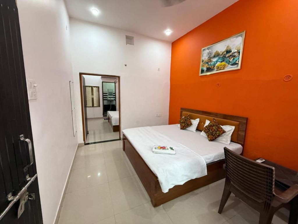 a bedroom with a bed with an orange wall at Shree Balaji home stay Ayodhya contact number 92782-97365 in Ayodhya