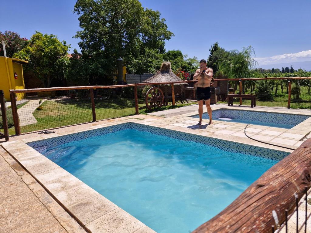 a woman standing next to a swimming pool at Cabañas El Sauce in Albardón