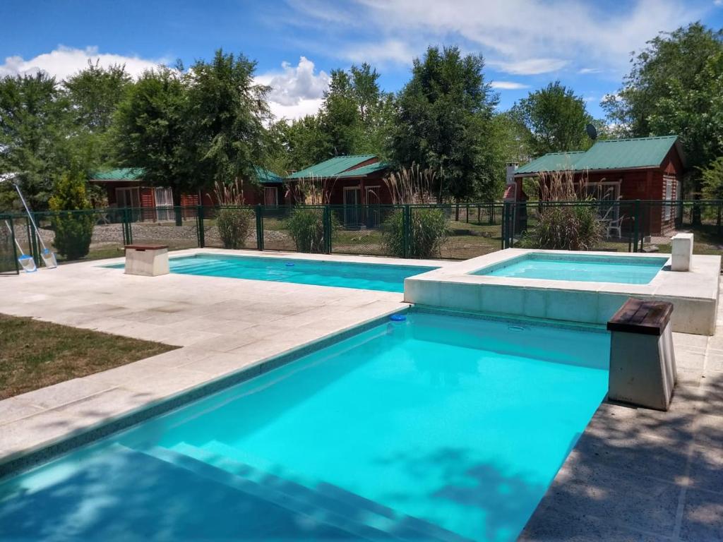 ein Swimmingpool mit einem Haus im Hintergrund in der Unterkunft Cabañas Esmeralda in Villa Ciudad de America