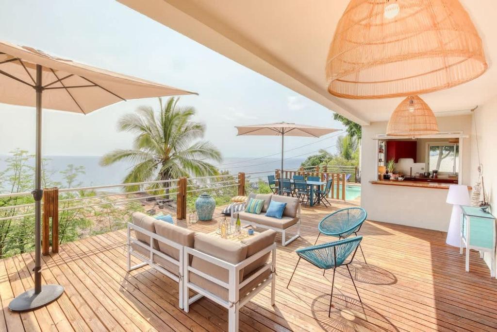 Un patio con mesa, sillas y sombrillas. en Villa Kap Grand Large, en Saint-Leu