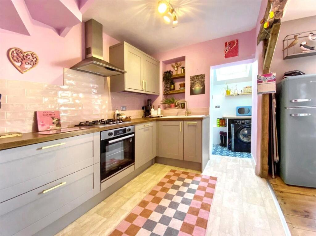 a kitchen with white cabinets and pink walls at Drew Street Digs in Brixham