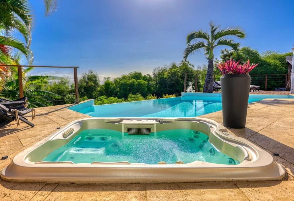 a hot tub sitting on a patio next to a swimming pool at Villa spa Grand Anse in Petite Île
