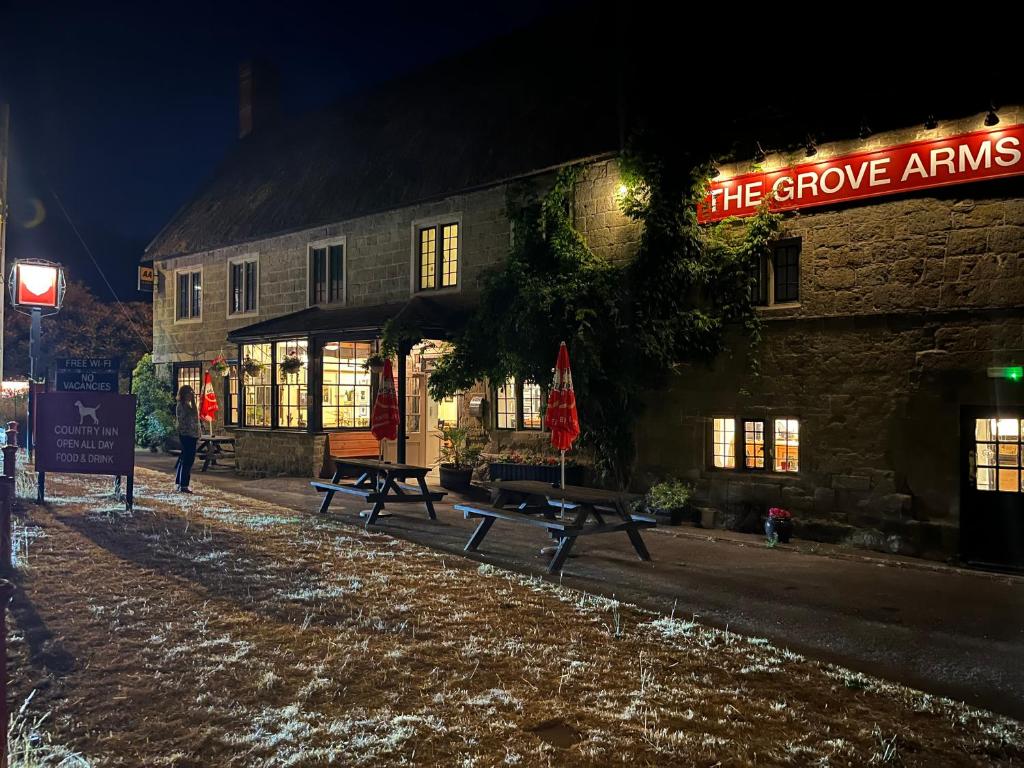a building with benches in front of it at night at The Grove Arms 