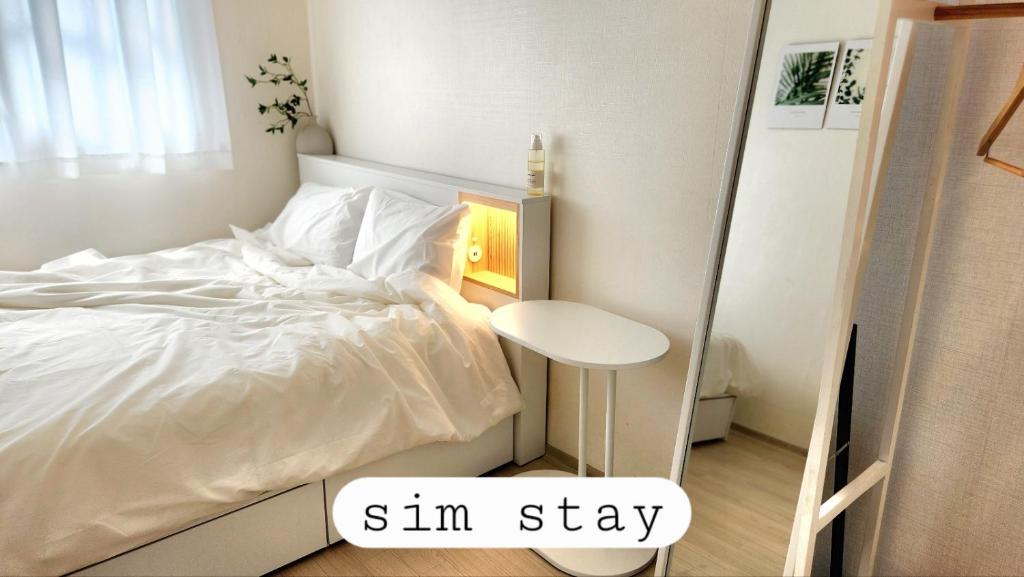 ein Schlafzimmer mit einem weißen Bett und einem kleinen Tisch in der Unterkunft Sim stay심스테이-매일 침구세탁clean bed in Mŏnnae