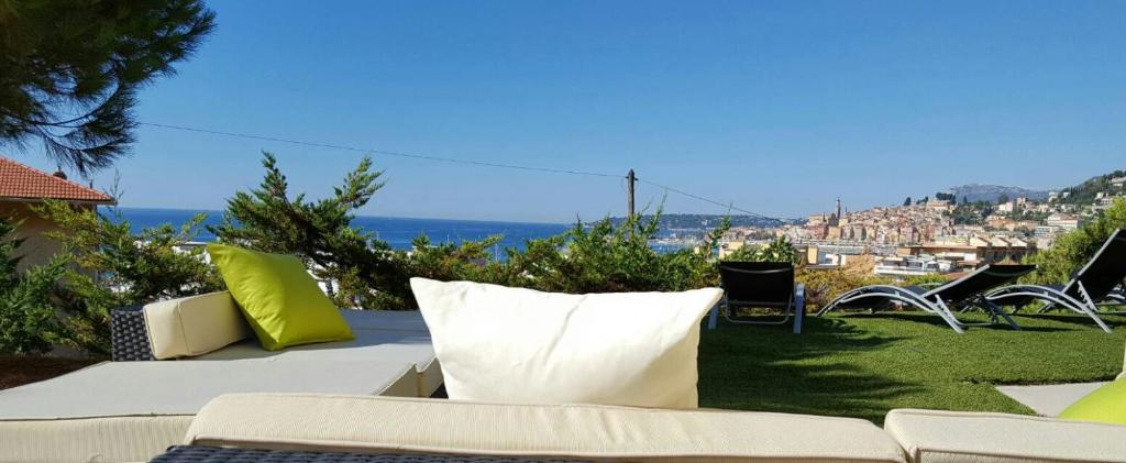 a couch with pillows sitting on top of a yard at Cap au Sud,Vue panoramique mer,piscine in Menton