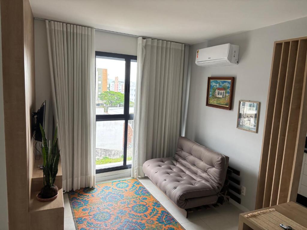 a living room with a leather couch in front of a window at Apt próximo a UFSC in Florianópolis