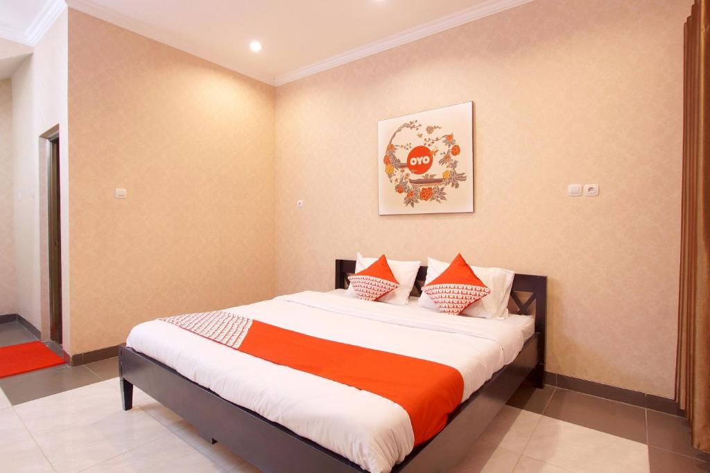 a bedroom with a bed with orange and white sheets at Hotel O near UGM formerly Bayang Brothers Guest House in Yogyakarta