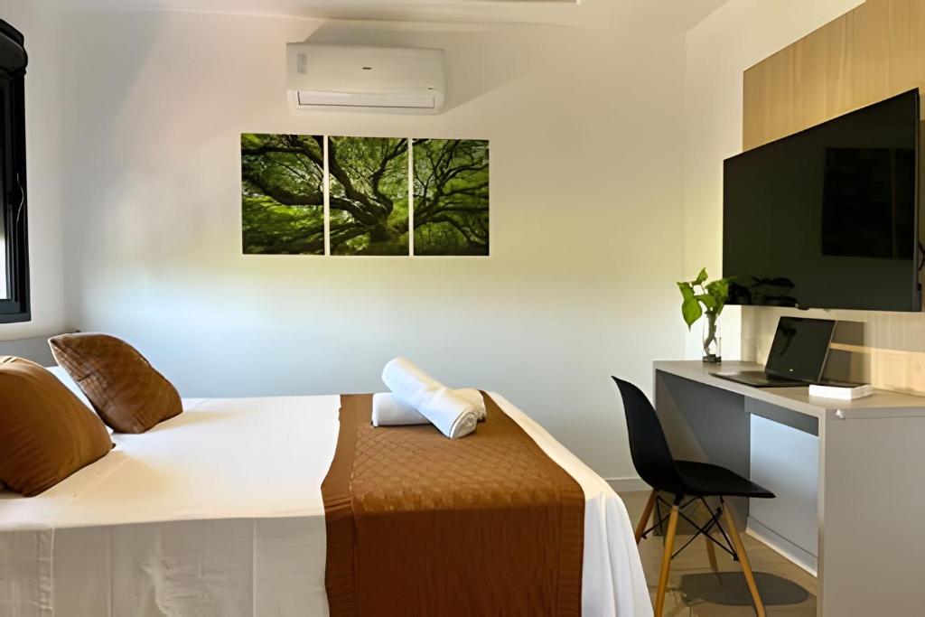 a bedroom with a bed and a desk with a computer at Aptos 1 ou 2 quartos no Centro com Piscina e Academia in Maringá