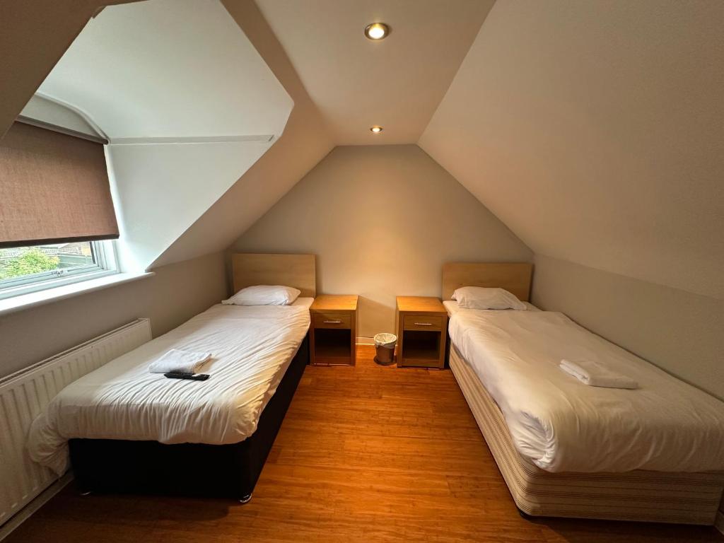 ハイ・ウィカムにあるCavendish Hotelのベッド2台と窓が備わる屋根裏部屋です。