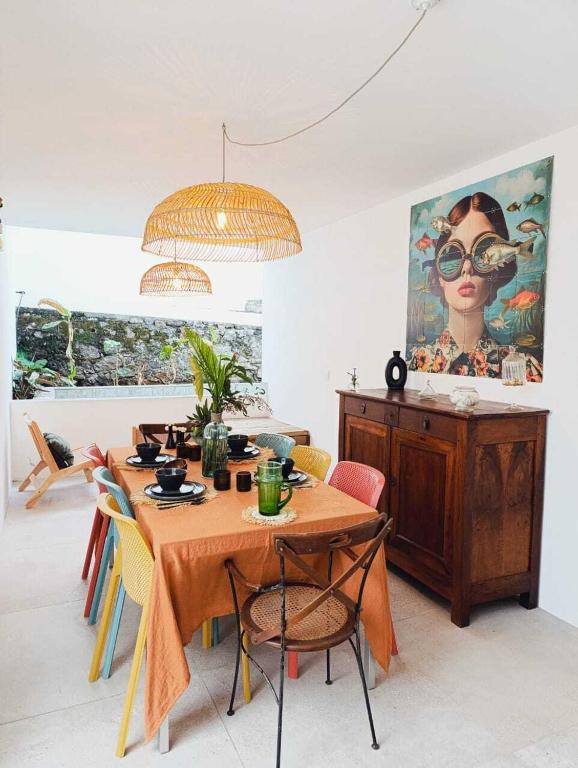 a dining room with a table with chairs and a painting at La Kaz Banian in Saint-Pierre