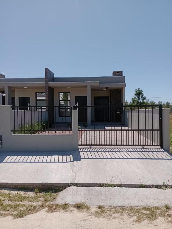 a house with a fence in front of it at Paraiso das ondas primeira quadra do mar in Balneário Gaivotas